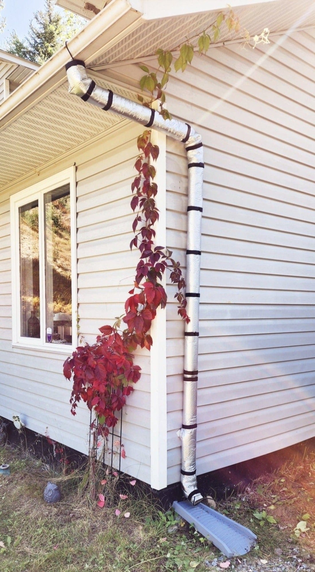 The Downspout Insulation wrapped around a downspout on a house with a heat cable.